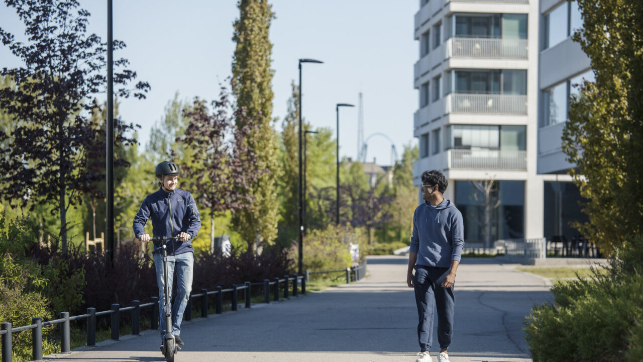 Kävelijä ja sähköpotkulautailija liikenteessä.