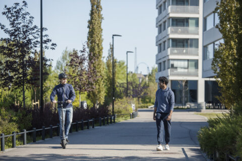 Kävelijä ja sähköpotkulautailija liikenteessä.