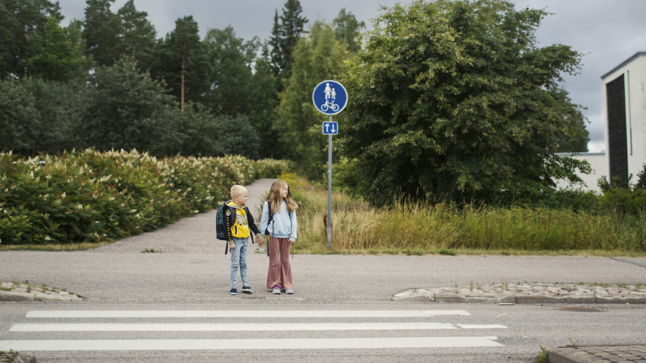 Kaksi koululaista suojatien edessä.