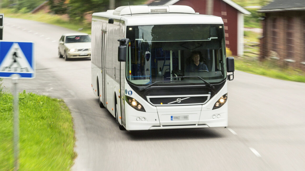 Linja-auto ajamassa vauhdilla tiellä.