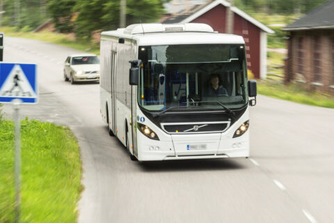Linja-auto ajamassa vauhdilla tiellä.