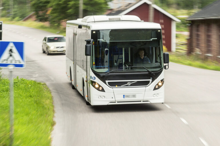 Linja-auto ajamassa vauhdilla tiellä.